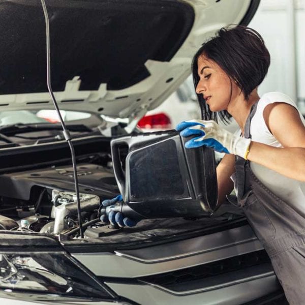 lady pouring transmission fluid into car